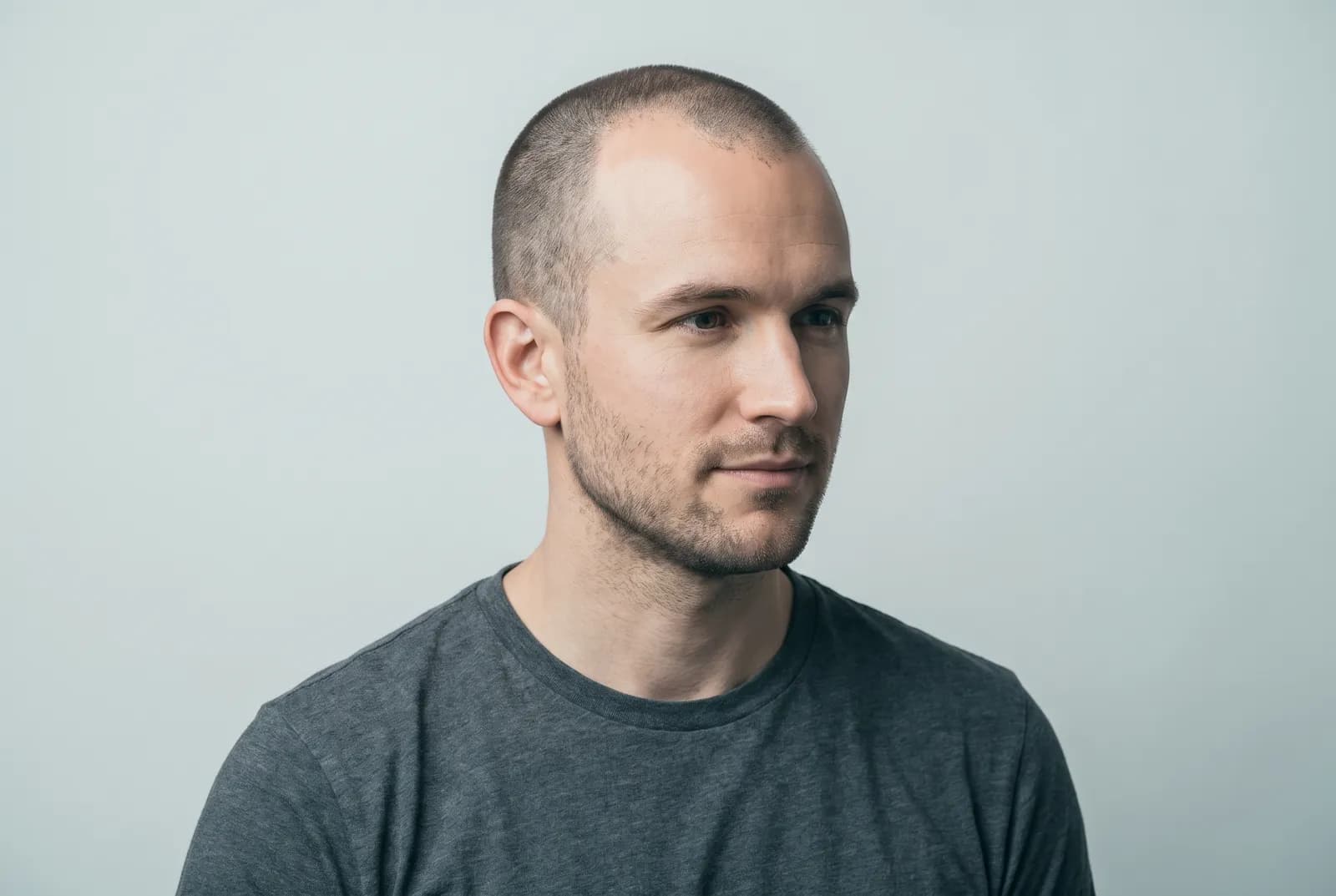Man with an M-shaped receding hairline wearing a short buzz cut, studio portrait