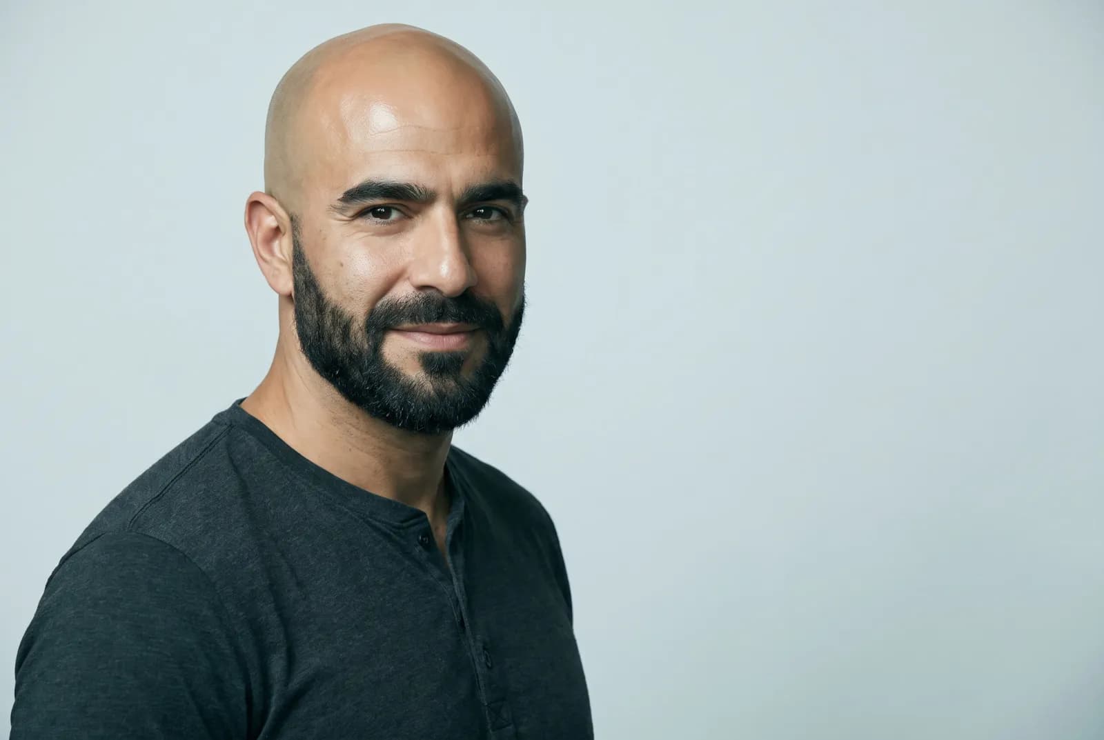 Confident bald man with a full well-groomed beard, studio portrait